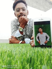 Portrait of smiling young man using mobile phone in grass
