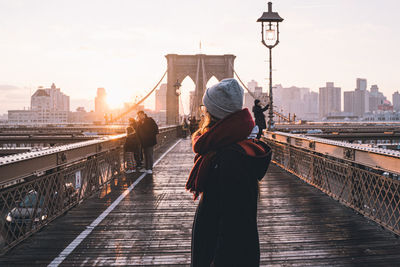 Rear view of woman on bridge over river in city