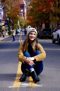 Portrait of smiling young woman sitting in road 