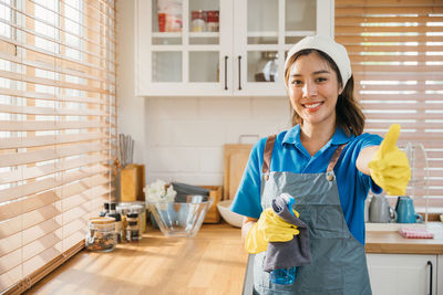 Portrait of young woman standing in kitchen