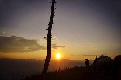 Silhouette people on land against sky during sunrise