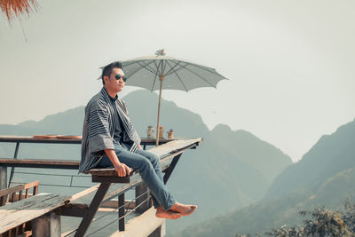 Young man looking at observation point against mountains