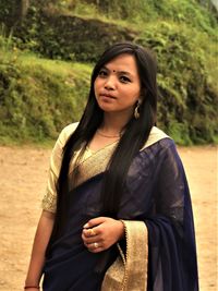 Portrait of young woman in sari standing on field