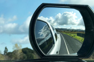 Reflection of sky on side-view mirror of car