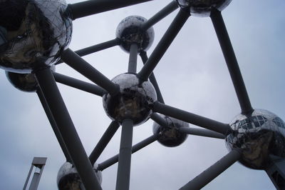 Low angle view of metal wheel against sky