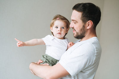 Happy father young man and baby girl little daughter having fun in children room at home