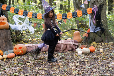 Arab girl in halloween costume and witch hat with broom in halloween decoration outdoor