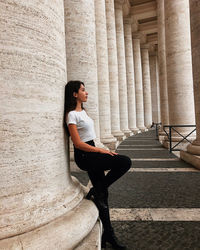 Side view of young woman leaning on column