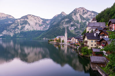 Houses by lake and mountains against sky