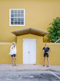 Full length of sisters standing against building