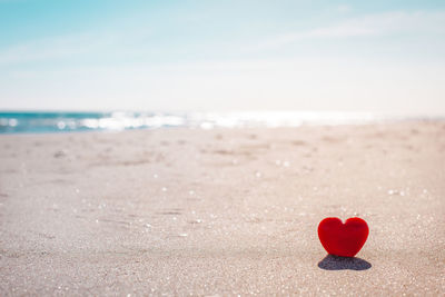 Heart shape on sand at beach against sky
