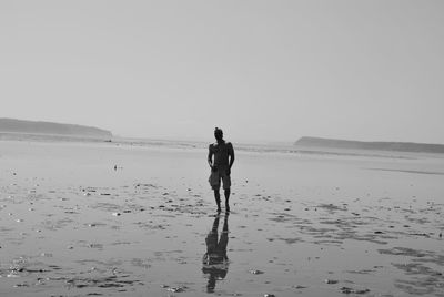 Men walking on beach against clear sky