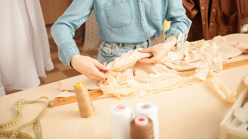 Seamstress in atelier works with beige fabric, workshop. manual labor, small business. hands