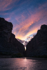 Scenic view of sea and mountains against sky during sunset