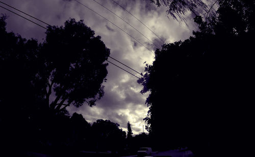 Low angle view of power lines against cloudy sky