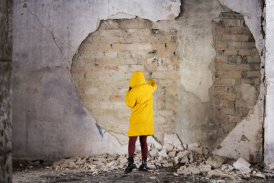 Rear view of woman standing against wall