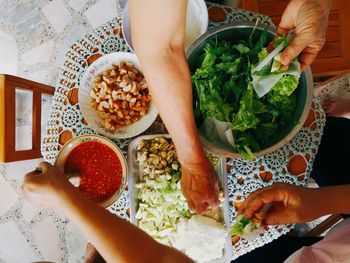 Cropped hands of friends having food at home