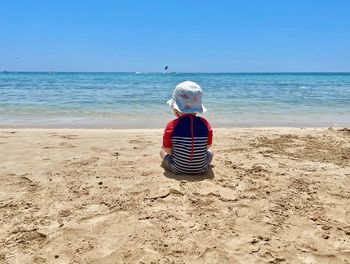 Rear view of boy sitting on beach