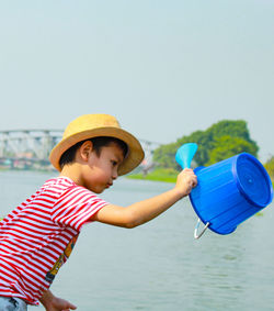 Boy holding bucket at riverbank