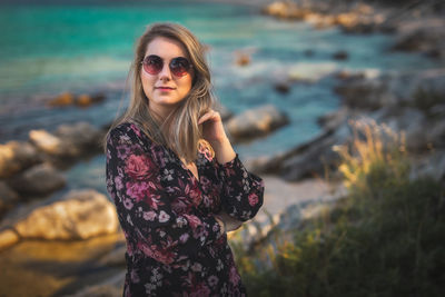 Portrait of young woman standing against mountain