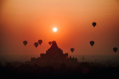 Silhouette of hot air balloons against sky during sunset