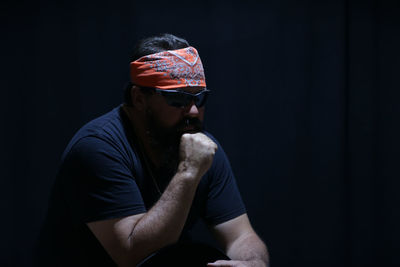 Young man wearing sunglasses against black background