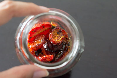 Female hand holding a pot with tomatoes confit