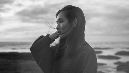 Close-up of young woman at beach against sky