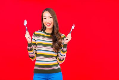 Portrait of a smiling young woman against red background