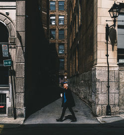 Side view of man walking on street amidst buildings