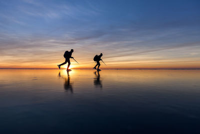 People long-distance skating at sunset, vanern, sweden