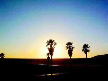 Silhouette palm trees against clear sky at sunset