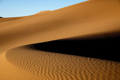 Sand dune in desert against clear sky