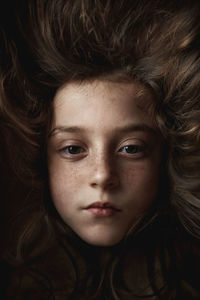 The girl's face appears on a dark hair background. portrait of a girl shot in the studio.
