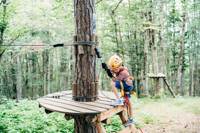 Full length of man climbing on tree trunk in forest