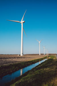 Windmill on field against clear blue sky