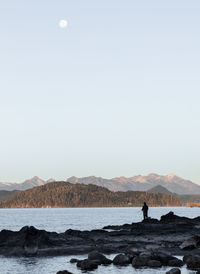 Man fishing in lake between mountains