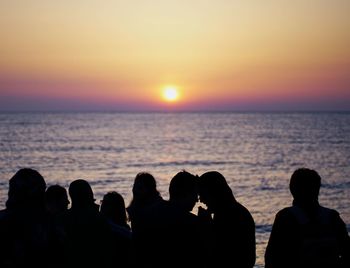 Silhouette people on beach against clear sky during sunset