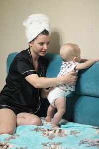 Young mother with baby sitting on the couch at home