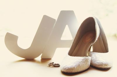Alphabets and high heels with wedding rings on table