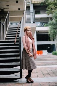 Portrait of woman standing by staircase