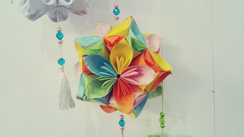 Close-up of colorful paper decoration hanging against wall