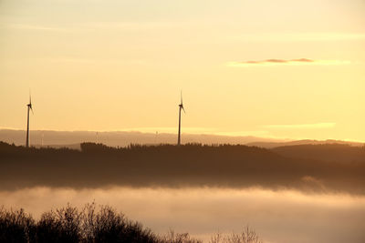 Silhouette of wind turbine against sky during sunset