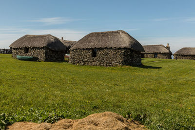 Built structure on field by houses against sky