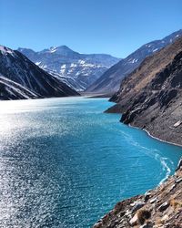 Scenic view of lake and mountains against clear blue sky