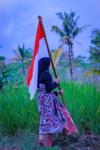 Rear view of woman with umbrella on field