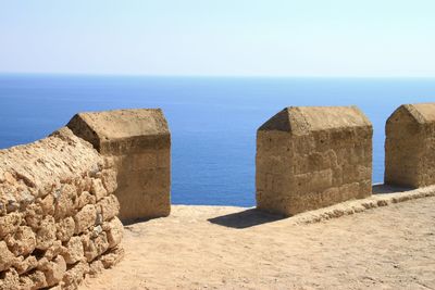 Stone wall by sea against clear sky