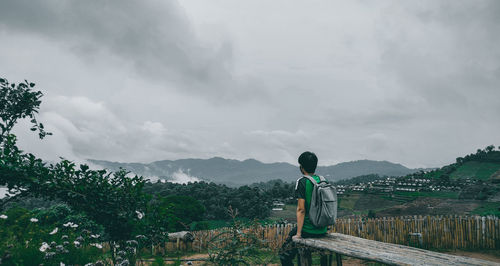 Rear view of man looking at mountain against sky