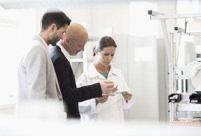 Female engineer and businessmen discussing machine in manufacturing plant