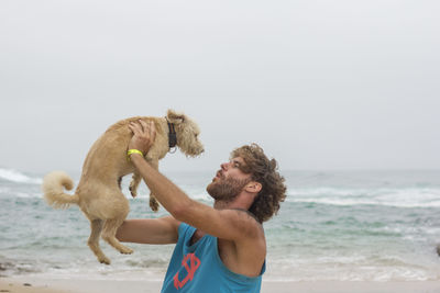 Man with dog playing on beach 